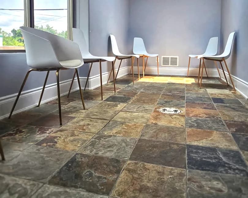The waiting room at Clarkson Village Dental, with a row of chairs along a window, a skylight overhead and a slate tile floor